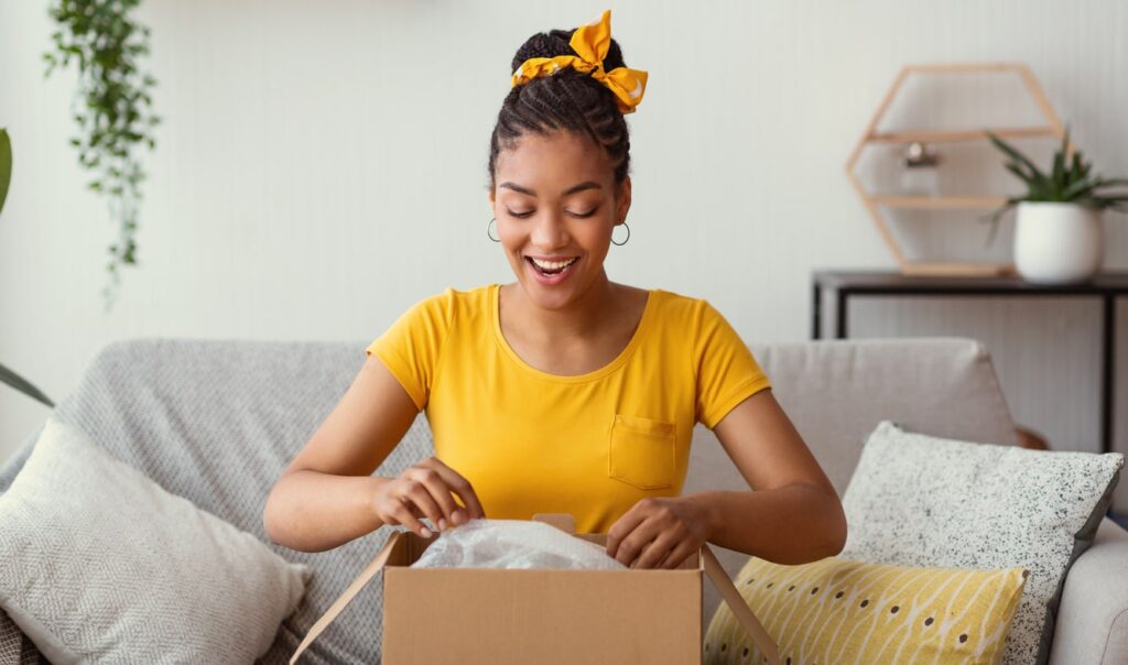 A happy woman opening a package bought with e-gift cards at home